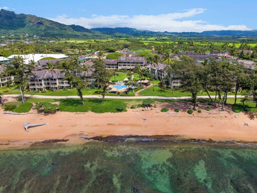 An aerial view of a resort with multiple buildings, a beach, and clear turquoise waters.