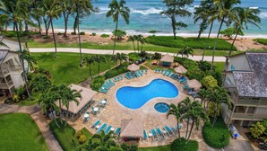 A resort with a circular pool, lounge chairs, and a view of the ocean. - Aston Islander on the Beach (Kapaa)