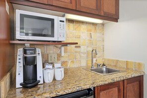 A kitchen with a microwave, coffee maker, and sink.