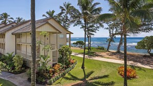 A beachfront hotel with a two-story structure, a covered outdoor area, and a view of the ocean. - Aston Islander on the Beach (Kapaa)