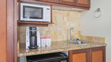A kitchen with a microwave, coffee maker, and sink.