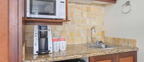A kitchen with a microwave, coffee maker, and sink.