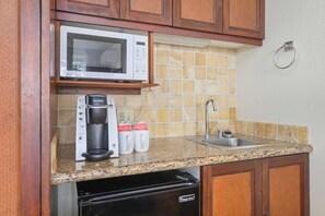 A kitchen with a microwave, coffee maker, and sink.