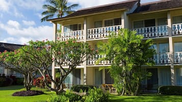 A multi-story hotel with balconies, lush greenery, and a well-maintained lawn.