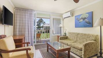 A living room with a sofa, armchair, coffee table, and a flat-screen TV.