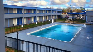 Un motel con piscina, estación de servicio y aparcamiento.