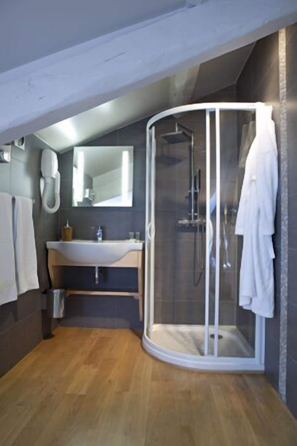 Un baño moderno con cabina de ducha de vidrio, lavamanos y espejo.