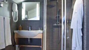 Un baño moderno con cabina de ducha de vidrio, lavamanos y espejo.