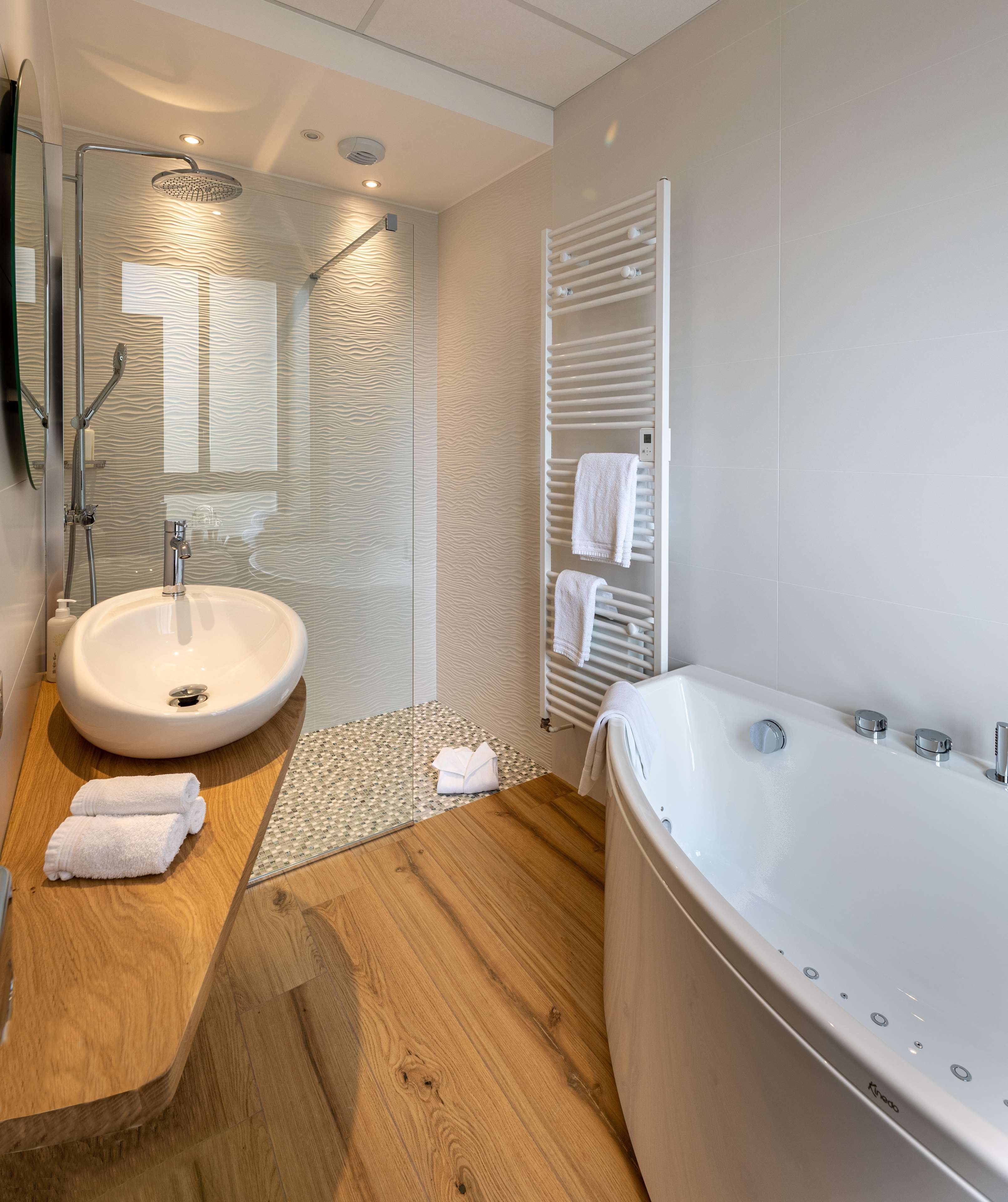 A modern bathroom with a freestanding bathtub, a round sink, and a glass shower enclosure.