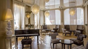 A spacious lounge with a grand piano, comfortable seating, and large windows allowing natural light.