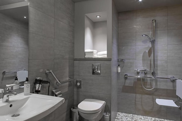 A modern bathroom with a sink, toilet, and walk-in shower.