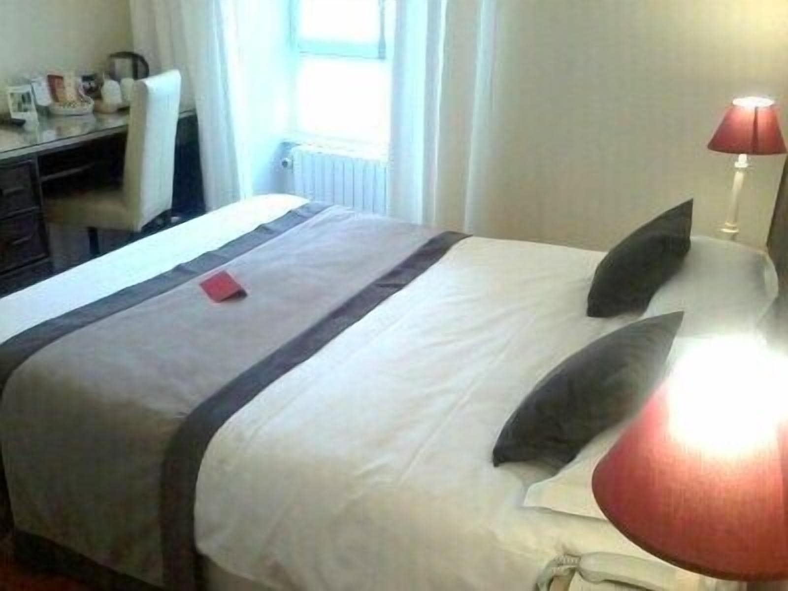 Une chambre d’hôtel avec un lit, un bureau et une lampe.