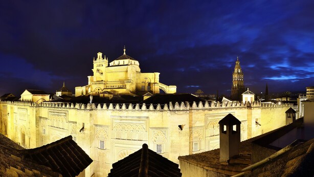 A historic building with a prominent dome and a tall tower, surrounded by a fortified wall with decorative elements.