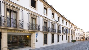 A hotel facade with ornate iron balconies, a clear entrance, and a sign reading "HOTEL EL CONQUISTADOR".