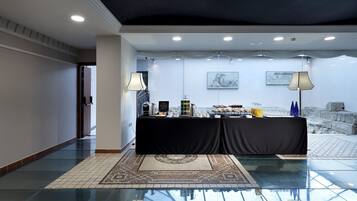 Rebedor d'hotel amb un sostre estrellat, una barra de buffet amb menjar i begudes, i vista a un paisatge rocos des d'una paret de vidre.