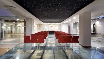 Una sala de conferencias con techo estrellado, sillas rojas y una mesa de vidrio.