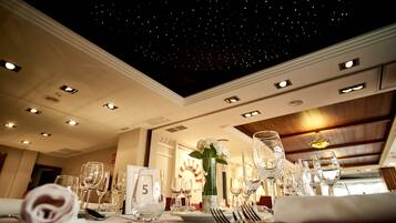 A dining area with a starry ceiling, neatly set tables, and a number '5' sign on the table.