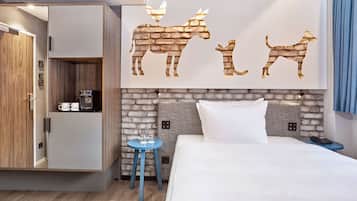 Habitación de hotel con cama, mesita de noche, una pequeña mesa auxiliar azul, armario y un cuadro en la pared con animales.