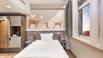 Une chambre d’hôtel avec un grand lit, une armoire, une petite table avec une machine à café et un mur décoré de découpes d’animaux.