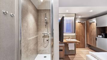 A modern bathroom with a glass-enclosed shower, a vanity with a sink, and a large mirror.