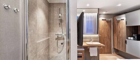A modern bathroom with a glass-enclosed shower, a vanity with a sink, and a large mirror.