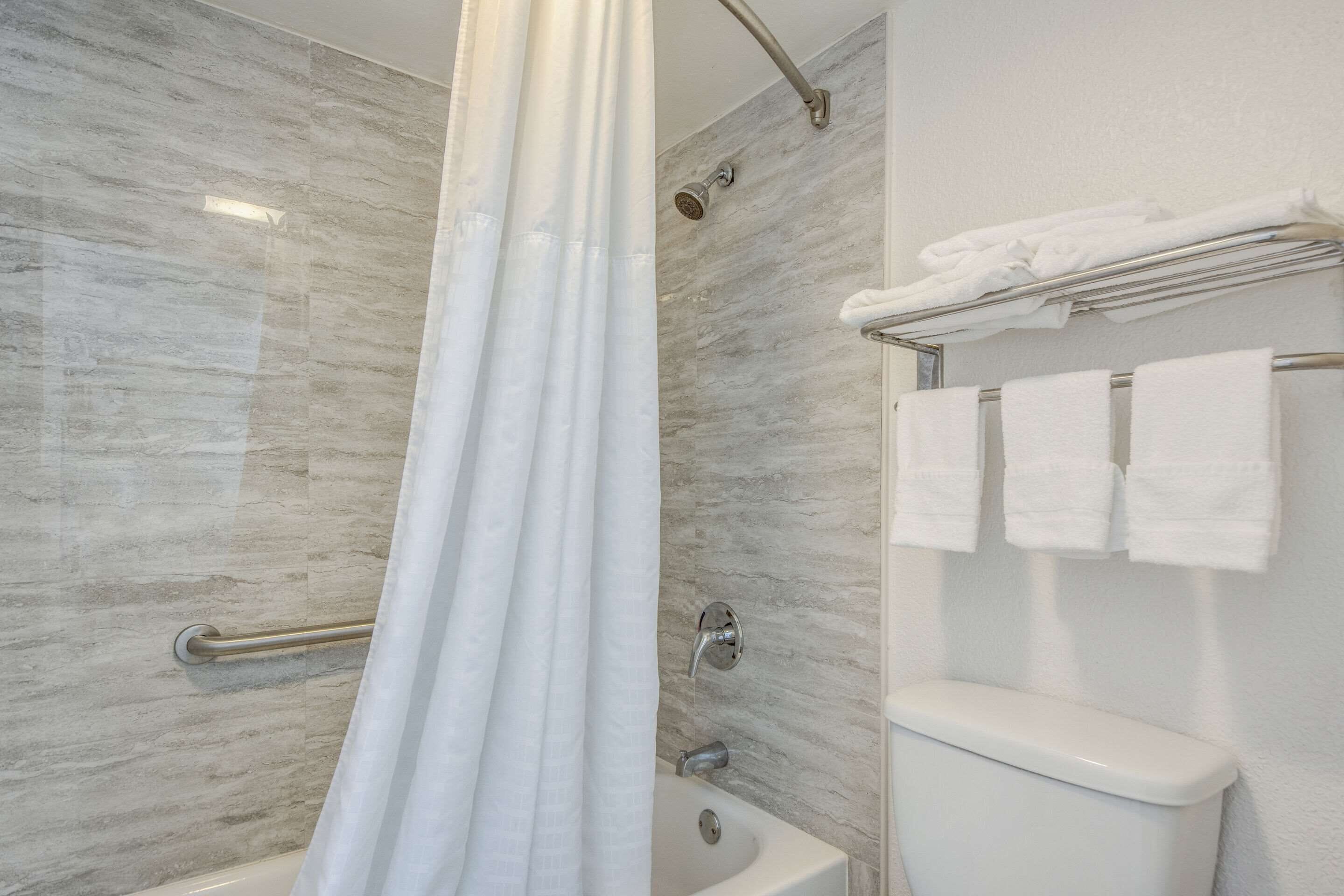 A modern bathroom with a shower, toilet, and towel rack.