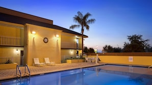 A hotel with a swimming pool, outdoor seating, and a palm tree. - Rodeway Inn Port Richey North (Port Richey)