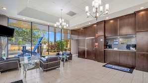 A hotel lobby with seating, a reception desk, and large windows overlooking a landscaped area. - Rodeway Inn Port Richey North (Port Richey)
