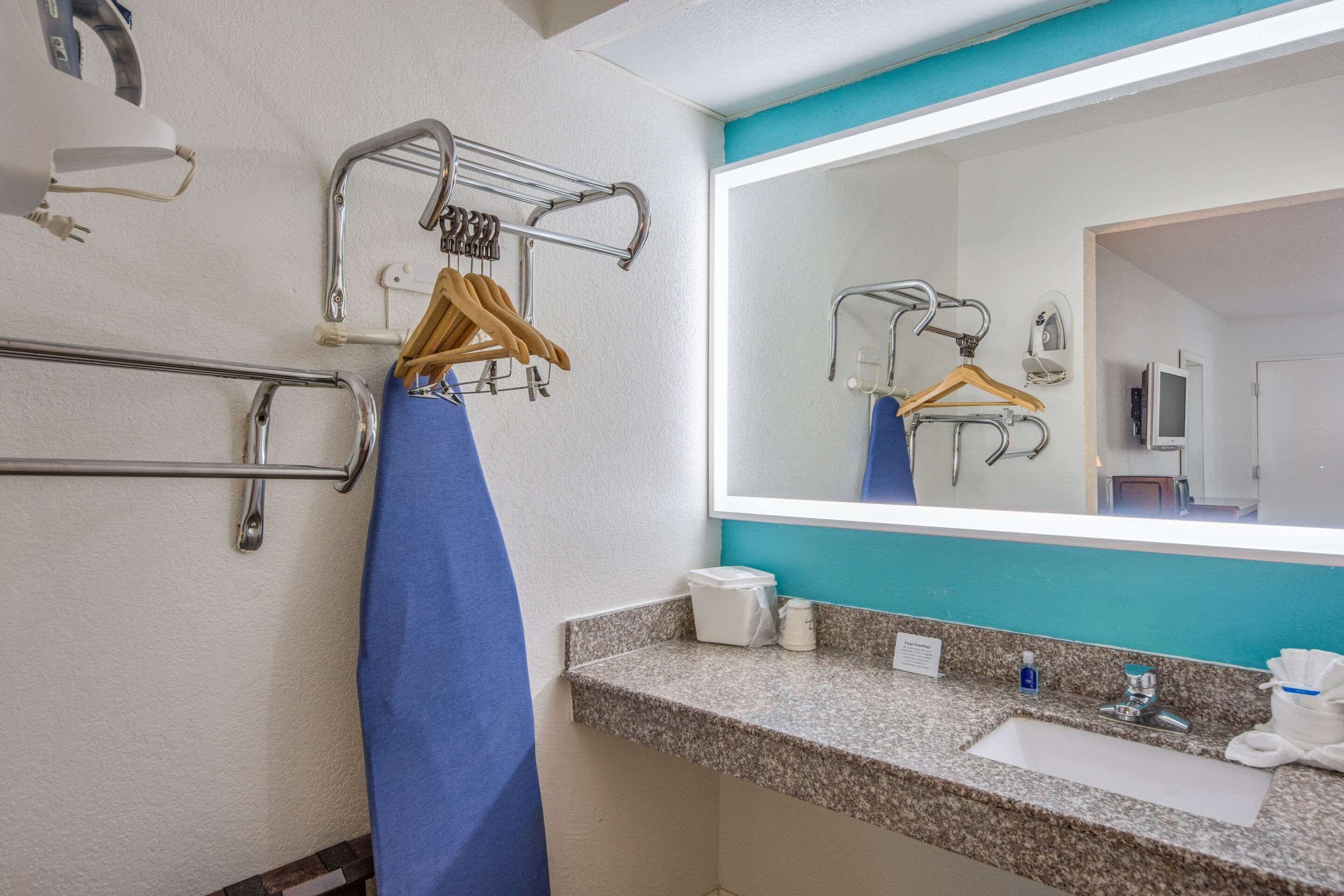 A bathroom with a sink, mirror, towel rack, and hand dryer.