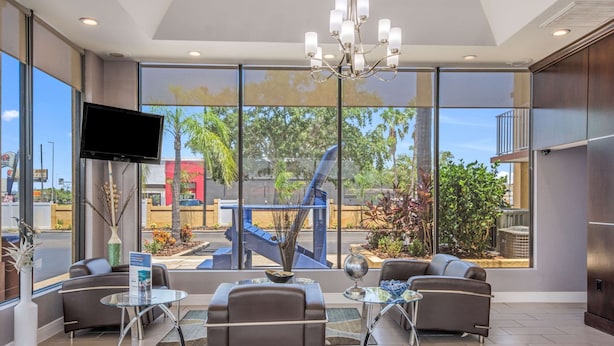 A modern lobby with large windows, a chandelier, and seating areas. - Rodeway Inn Port Richey North (Port Richey)