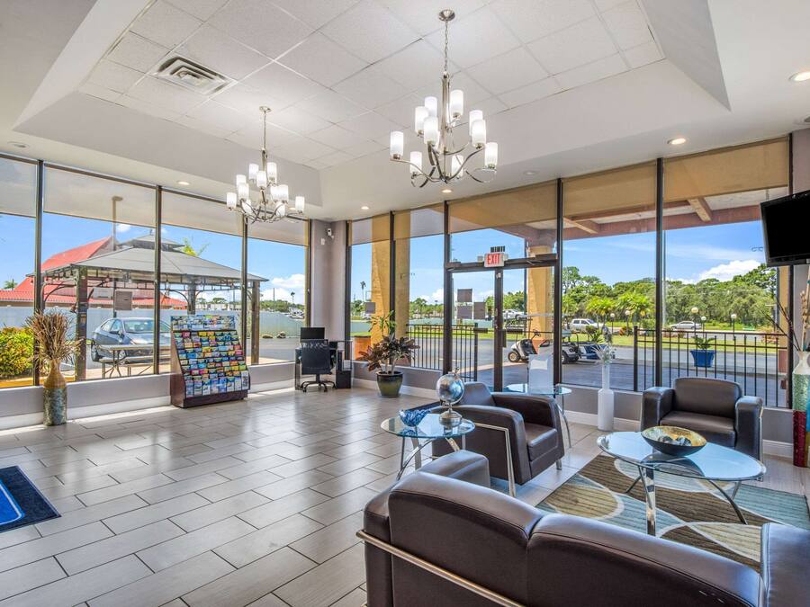 A spacious lobby with comfortable seating, large windows offering views of the parking area, and a chandelier.