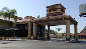 A building with a covered entrance, outdoor seating, and a sign indicating a maximum height restriction. - Rodeway Inn Port Richey North (Port Richey)