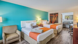A hotel room with two beds, a chair, a desk, and a bathroom visible through an open door. - Rodeway Inn Port Richey North (Port Richey)