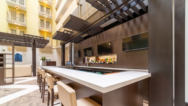 A modern bar area with a long counter, multiple seating options, and a variety of bottles. - Doubletree Suites by Hilton at The Battery Atlanta (Atlanta)