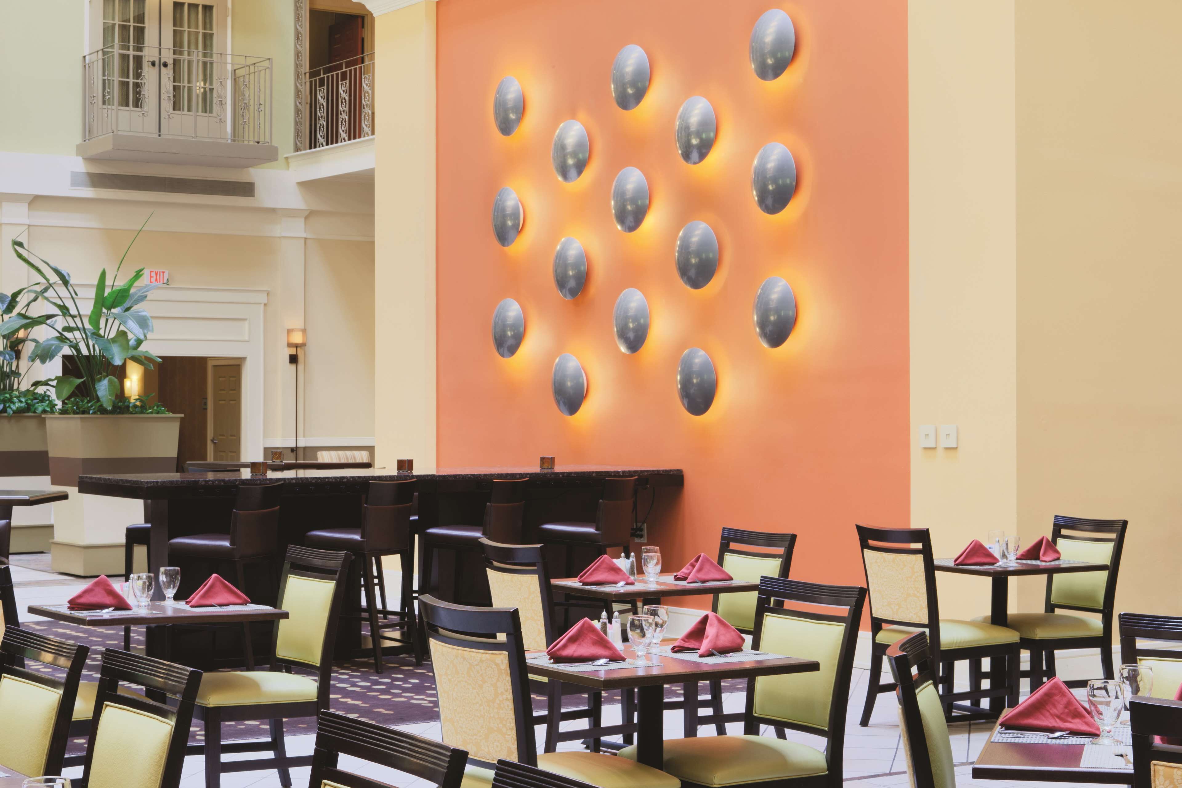 Un comedor con mesas y sillas, una pared con luces decorativas y una señal de salida.