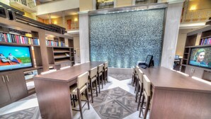 A modern library with a central island table, bookshelves, and a large wall with a textured pattern. - Doubletree Suites by Hilton at The Battery Atlanta (Atlanta)