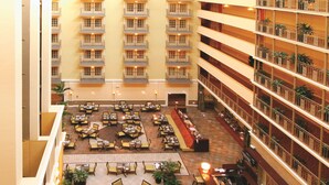 A multi-level hotel atrium with a central courtyard featuring outdoor seating, multiple floors with balconies, and a variety of dining areas. - Doubletree Suites by Hilton at The Battery Atlanta (Atlanta)