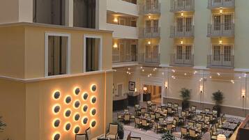 Un vestíbulo de hotel con varios pisos, un comedor con mesas y sillas, y una recepción.
