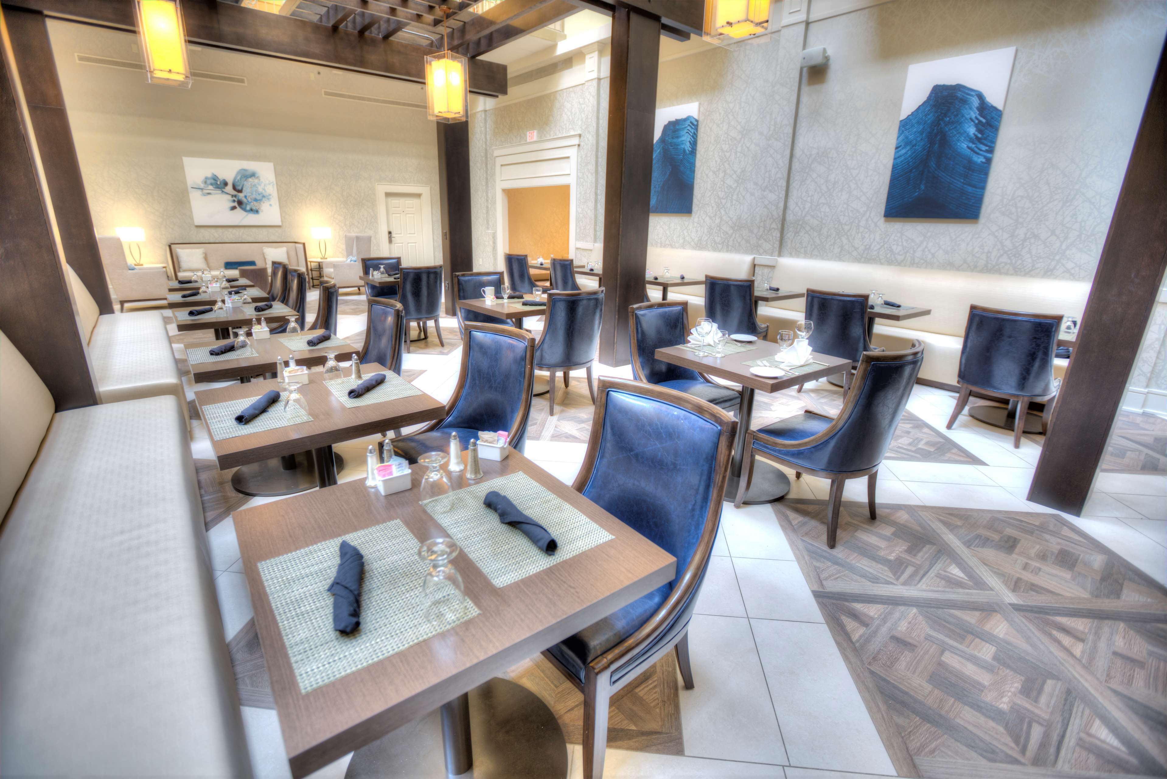 A hotel dining area with multiple tables and chairs, arranged in a spacious layout.