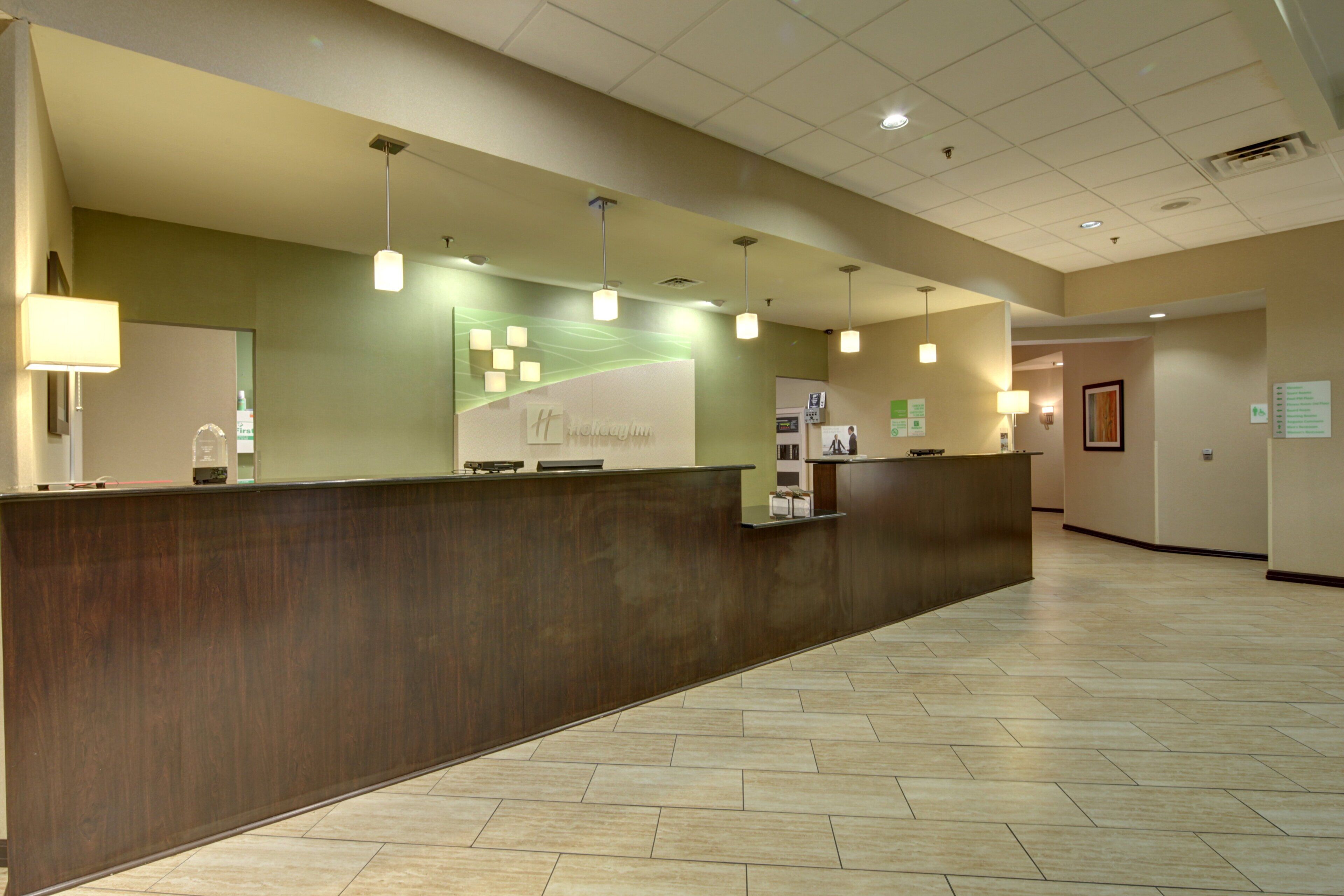 A reception desk with a wooden finish, overhead lighting, and a green accent wall.