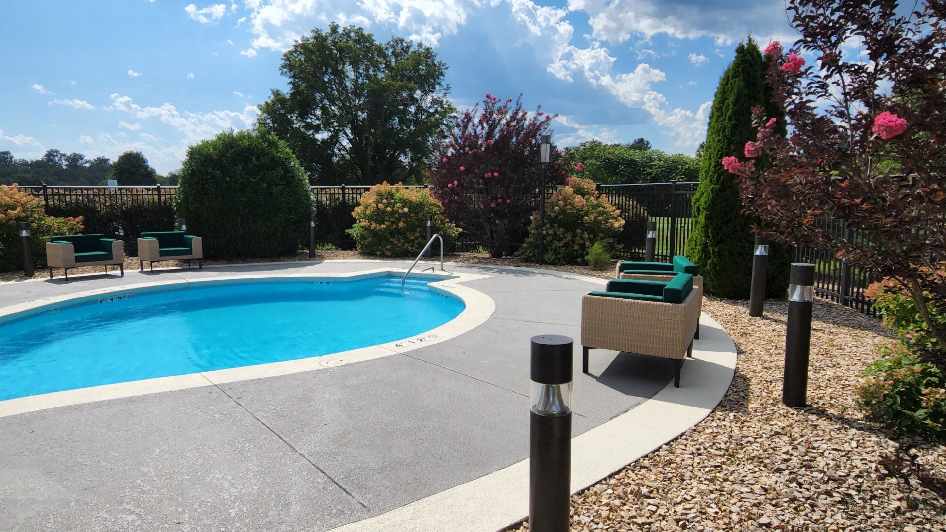 Una piscina con sillas de descanso y solárium pavimentado.