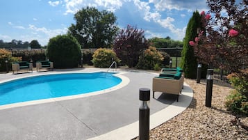 Una piscina con sillas de descanso y solárium pavimentado.