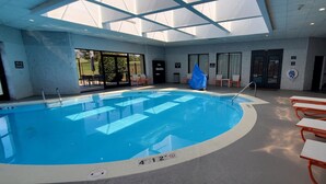 Une piscine intérieure à l’eau claire, entourée de chaises longues et d’un espace salon abrité.
