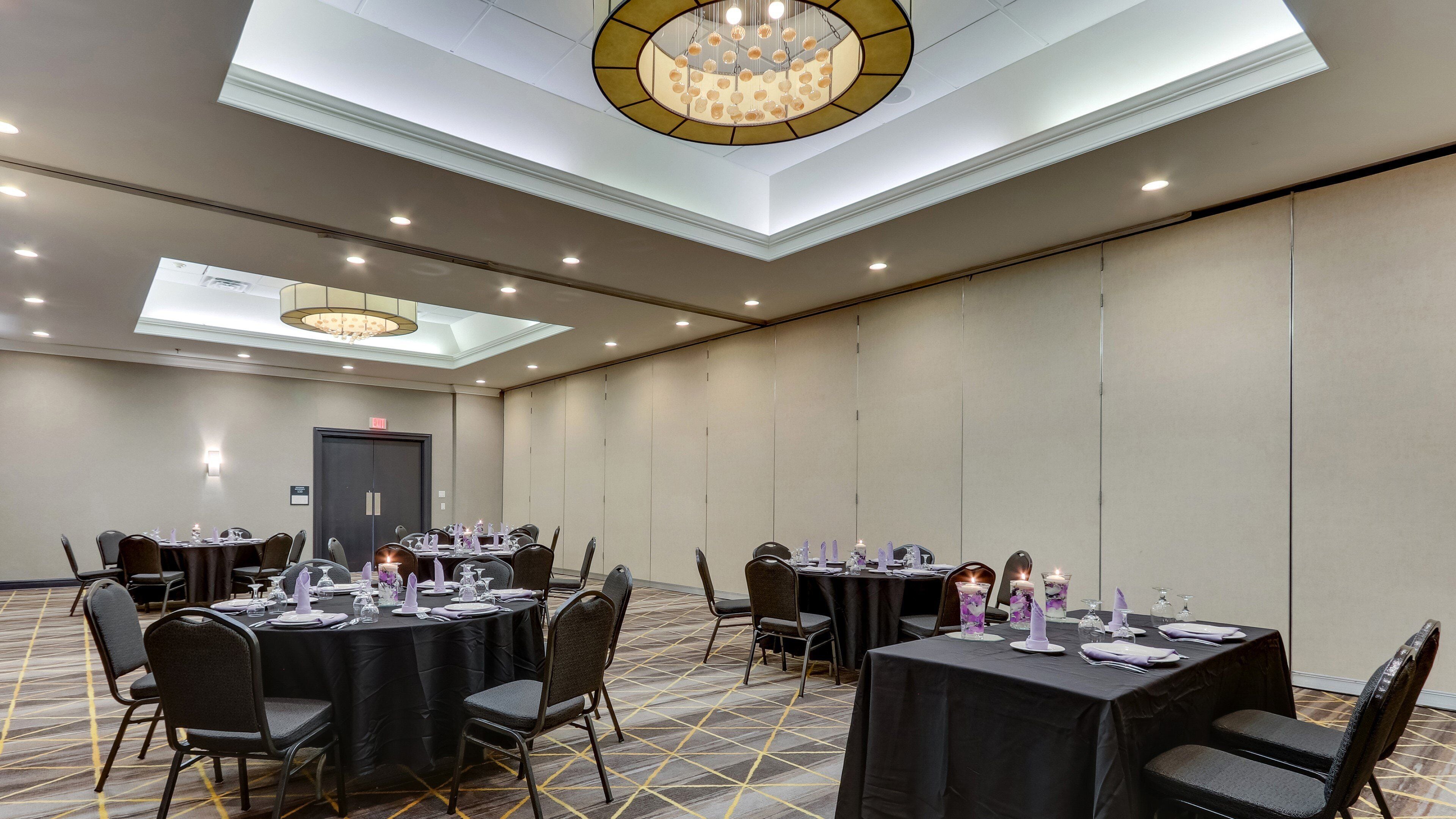 A conference room with round tables, chairs, and a chandelier.