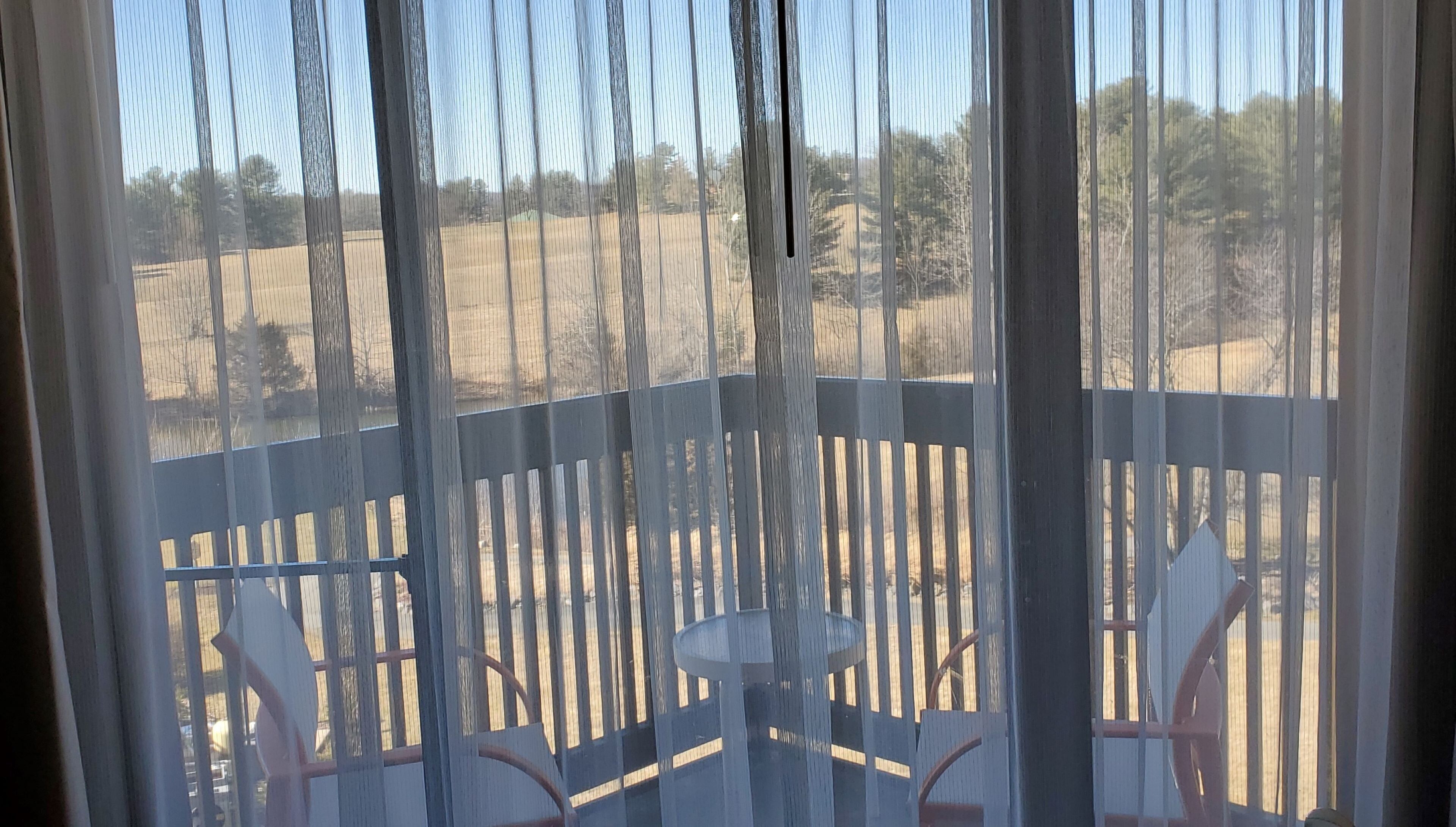 A view from a balcony with a wooden railing, a small table, and chairs.