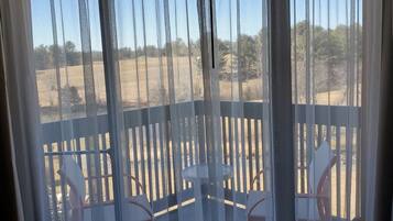 A view from a balcony with a wooden railing, a small table, and chairs.