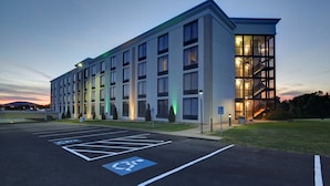 A modern building with a parking lot, marked handicapped spaces, and a staircase leading to the entrance. - Holiday Inn Staunton Conference Center by IHG (Staunton)
