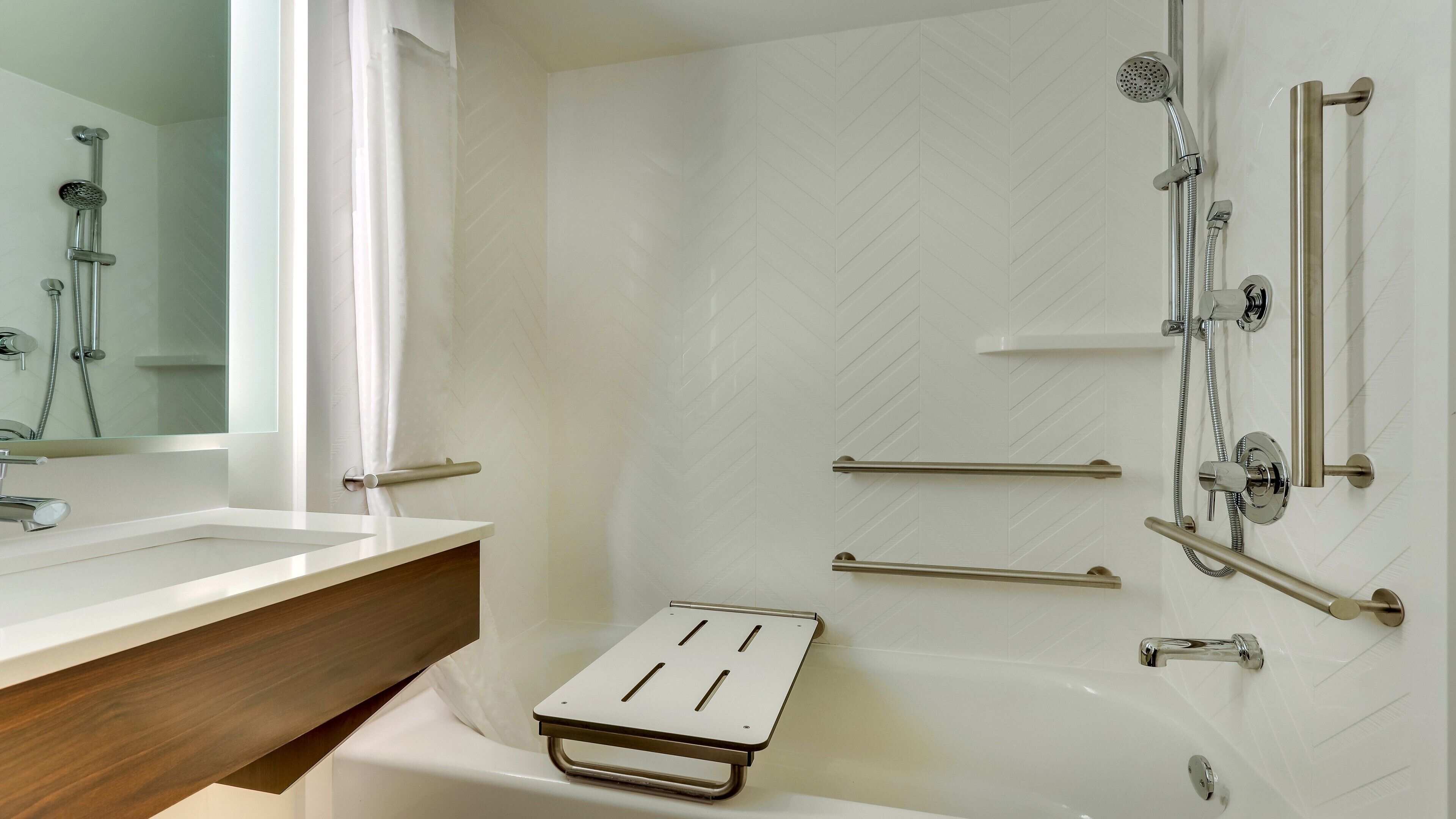 A modern bathroom with a bathtub, shower, and a vanity with a mirror.
