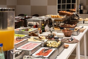 Buffet com diversas opções de comida, incluindo carnes, queijos e frutas.