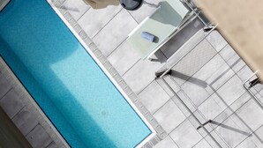 A rooftop pool with a clear blue water feature, surrounded by a tiled deck and furnished with outdoor seating and umbrellas. - Catalonia Diagonal Centro (Barcelona)